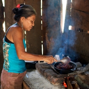 A woman cooking beans on a wood-burning stove